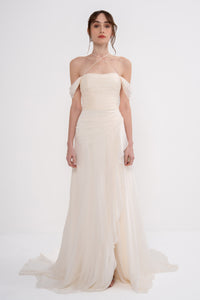 Elegant Harmonia Dress by Manel-Fashion displayed on a hanger, showcasing its flowing fabric and stylish design.