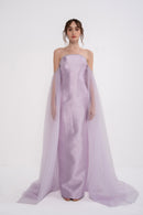 Elegant PANDORA dress by MANEL-FASHION displayed on a hanger with intricate fabric details and subtle color shades.
