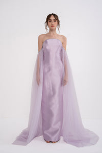Elegant PANDORA dress by MANEL-FASHION displayed on a hanger with intricate fabric details and subtle color shades.