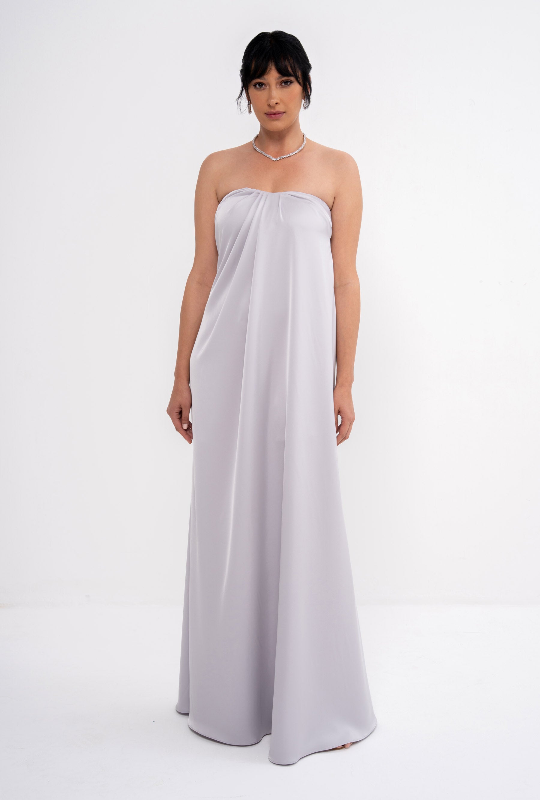 Grey CLEA dress by MANEL-FASHION hanging on a wooden hanger, showcasing its stylish design and fabric texture.
