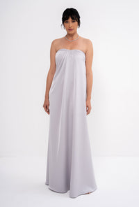 Grey CLEA dress by MANEL-FASHION hanging on a wooden hanger, showcasing its stylish design and fabric texture.